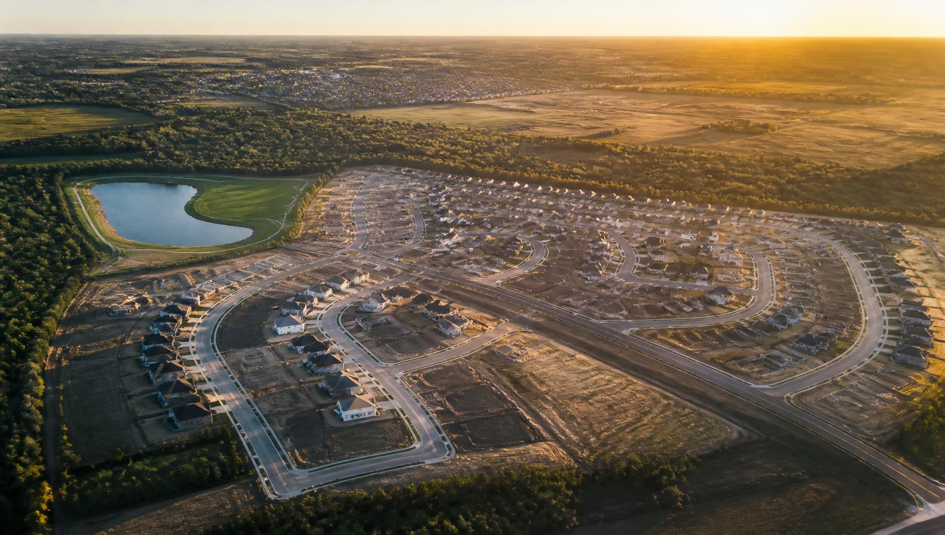 Aerial view of a master-planned residential development with finished streets and graded lots at golden hour
